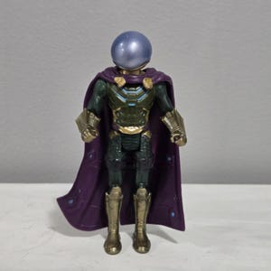May include: A Mysterio action figure, featuring a metallic blue spherical helmet and a purple cape. The figure has a green and gold armored suit with gold boots and gauntlets. The cape has a diamond pattern.