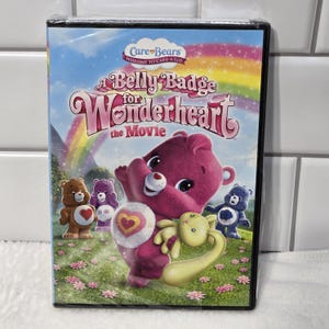 Może przedstawiać: Okładka DVD do filmu o Care Bears « Odznaka dla Wonderheart ». Na okładce widnieje Wonderheart, różowy Care Bear z odznaką w kształcie serca na brzuchu, otoczony innymi Care Bears.