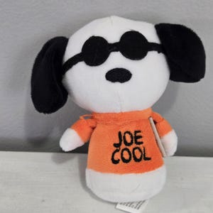 Peut inclure: Une tasse en céramique blanche avec une anse noire et le texte "But First, Coffee" en gras noir. La tasse est posée sur une surface en bois. La tasse mesure environ 10 cm de haut.