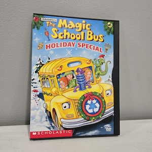 May include: A DVD case for "The Magic School Bus Holiday Special." The cover shows a yellow school bus with passengers, a wreath, and a green lizard in a Santa hat. The title is in red and yellow.