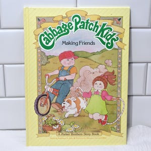 Peut inclure: Un livre d'histoires vintage "Cabbage Patch Kids" intitulé "Making Friends". La couverture présente des illustrations d'enfants, d'un chien et d'un vélo sur un fond jaune. Le livre est un Parker Brothers Story Book.
