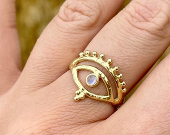 May include: Gold ring with a moonstone eye design. The ring has a textured finish and a delicate, intricate design.