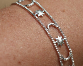 May include: A silver bracelet with a delicate chain and multiple charms in the shape of moons and stars.