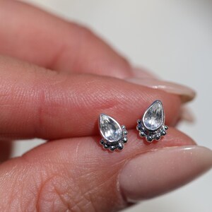 Peut inclure: Une paire de boucles d'oreilles en argent en forme de larme avec des pierres claires et une bordure perlée.