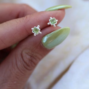 Peut inclure: Une paire de boucles d'oreilles en argent avec de petites pierres précieuses carrées vertes serties dans un cadre décoratif.