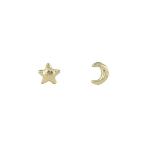 May include: A pair of gold-toned earrings featuring a star and a crescent moon design. The earrings have a textured, hammered finish.