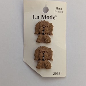 Könnte beinhalten: Zwei handbemalte braune Plastikknöpfe in Form von Hunden. Die Knöpfe befinden sich auf einer weißen Karte mit dem Text "La Mode" und "Handbemalt" sowie der Nummer "2968".