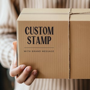 May include: A brown cardboard box with a string tied around it. The box has the text "CUSTOM STAMP WITH BRAND MESSAGE" printed on the front.