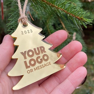 May include: Gold Christmas tree ornament with the text "2023", "YOUR LOGO", and "OR MESSAGE".
