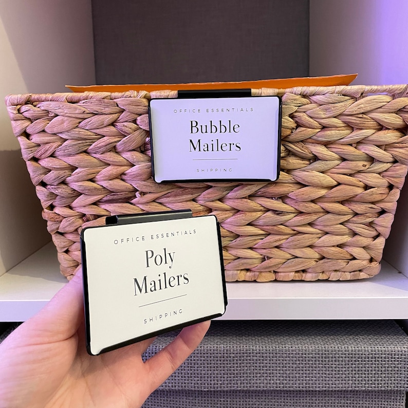 Puede incluir: Dos etiquetas blancas con texto negro y bordes negros, unidas a una cesta de mimbre. La etiqueta superior dice "Office Essentials Bubble Mailers Shipping". La etiqueta inferior dice "Office Essentials Poly Mailers Shipping".