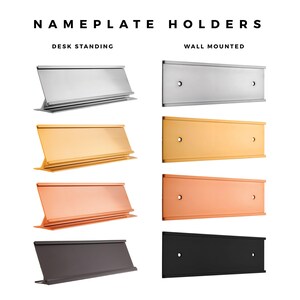 a collection of various desk and wall-mounted nameplate holders in different colors and designs, including silver, gold, orange, black, and plain black.
