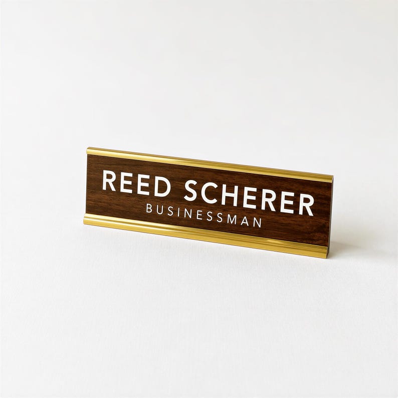 A wooden nameplate with the name 'Reed Scherrer' and 'Businessman' printed on it, placed on a white background.