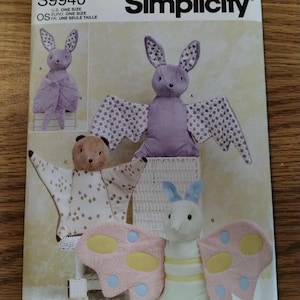 May include: Simplicity sewing pattern S9940 for stuffed animals. The envelope displays three plush toy designs: a purple bat with patterned wings, a tan bat with patterned wings, and a white insect with pink, yellow, and blue butterfly wings.