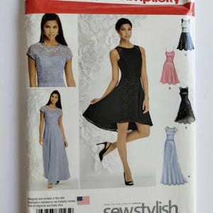 May include: Simplicity sewing pattern 1195 P5 for dresses in sizes 12-20. The envelope features illustrations of four dress variations, including a light blue lace-bodice gown, a black high-low dress, a pink dress, and a polka-dot dress.