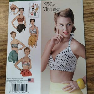 May include: A Simplicity 1426 R5 sewing pattern envelope for 1950s vintage style tops. The cover features illustrations of various halter and strapless crop tops, along with a photograph of a person wearing a white halter top with black polka dots.