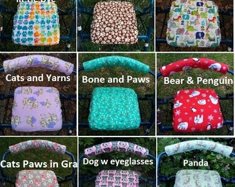 May include: Nine different walker seat and armrest covers. The covers are made of fabric with various animal and paw print designs. The designs include cats, dogs, penguins, bears, and dinosaurs. The text on the covers reads "Paws Hearts in Tie Dye", "Paws in Brown", "Dino", "Cats and Yarns", "Bone and Paws", "Bear & Penguin", "Cats Paws in Gra", "Dog w eyeglasses", and "Panda".