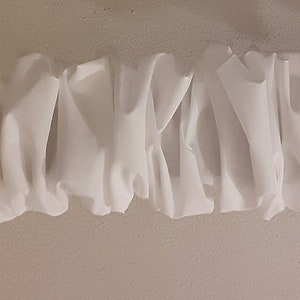 May include: White fabric ruched trim with a wavy, pleated design. The trim is made of a soft, lightweight material and is perfect for adding a touch of elegance to any project.