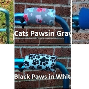 May include: Four different walker armrest covers. The covers are made of fabric and are in the following colors and patterns: black, gray with cat paw prints, blue, and white with black paw prints.