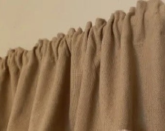 May include: A set of tan fabric valances with a gathered ruffle at the top. The valances are made of a textured fabric and have a simple, classic design.