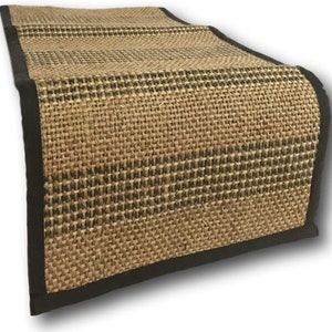 May include: A brown and black woven table runner with a black border. The runner has a textured woven pattern.