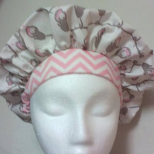 May include: A pink and white chevron patterned shower cap with a white background and brown bird print.