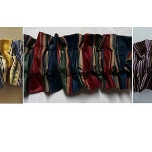 May include: Three different striped fabric valances with ruffled edges. The first valance is yellow and blue, the second is red, blue, and green, and the third is purple and brown.
