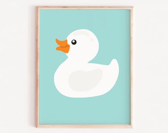 May include: A white rubber duck with an orange beak and feet on a light blue background. The image is framed in a light wood frame. The text "ART PRINTS FACTORY" is at the bottom of the image.