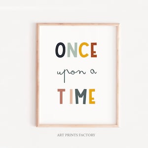 May include: A framed print with the text "ONCE upon a TIME" in colorful, stylized letters. The letters are in shades of black, yellow, green, red, and brown. The background is white. The print is framed in a light wood frame.