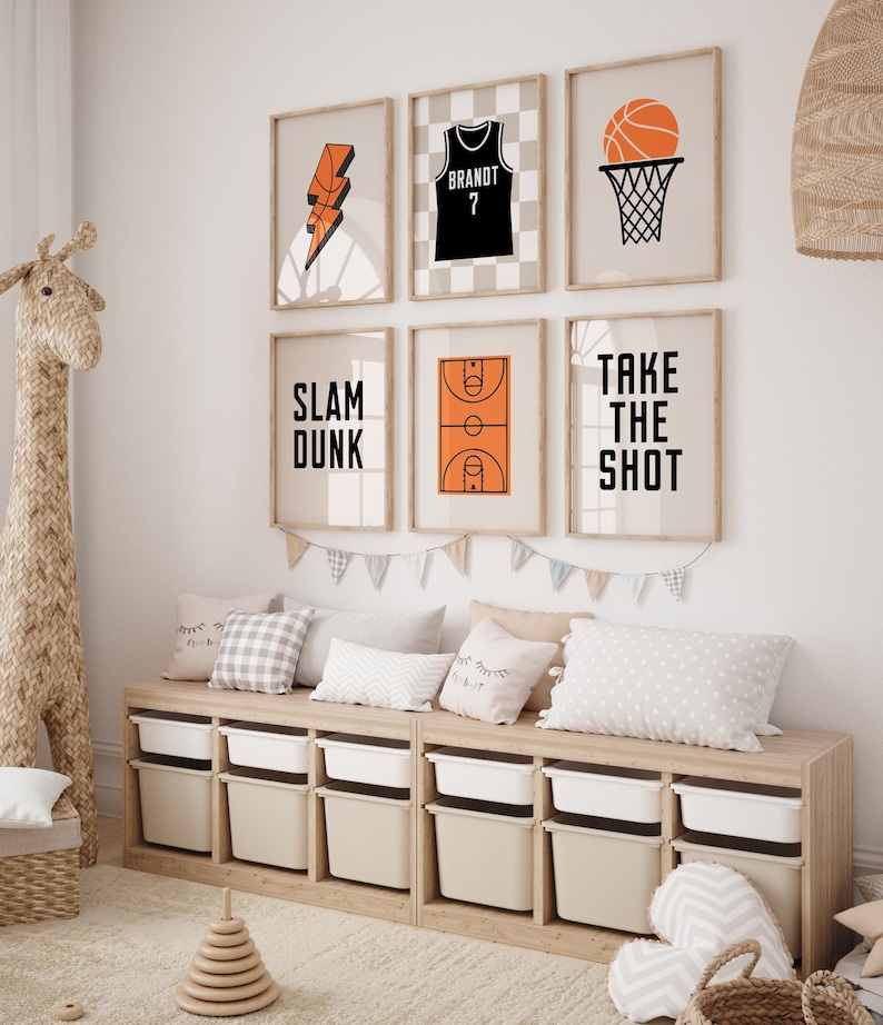 Peut inclure: Une chambre d'enfant avec un banc de rangement en bois avec six bacs de rangement blancs. Le mur est d&eacute;cor&eacute; de six impressions encadr&eacute;es sur le th&egrave;me du basketball. Les impressions repr&eacute;sentent un maillot de basket-ball, un panier de basket-ball, un terrain de basket-ball, un ballon de basket-ball avec un &eacute;clair et le texte "Slam Dunk" et "Take the Shot".