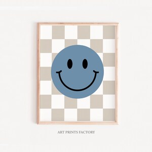 May include: A blue smiley face on a beige and white checkered background. The image is framed with a light wood frame. "ART PRINTS FACTORY" is printed below the image.