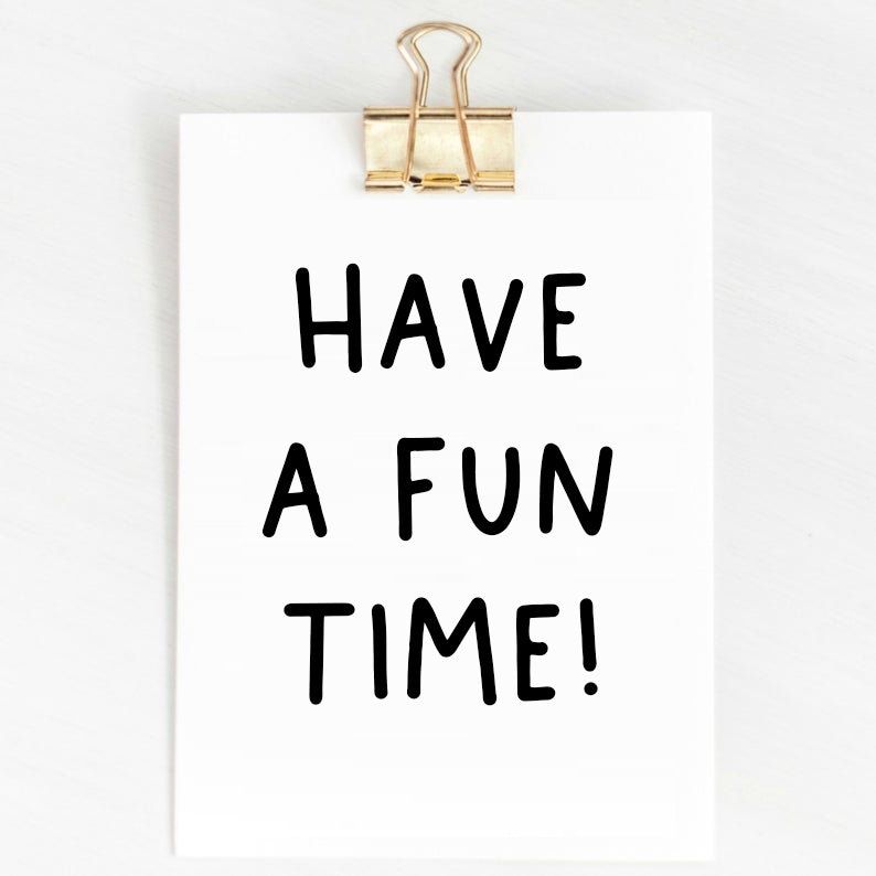 May include: A white card with black text that reads "Have a fun time!" The card is attached to a white wall with a gold paper clip.