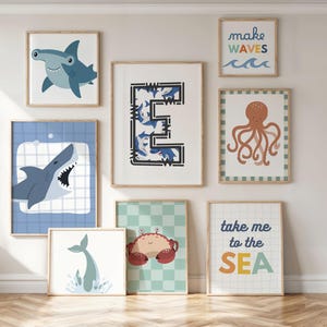 Puede incluir: Una colecci&oacute;n de l&aacute;minas art&iacute;sticas enmarcadas con vida marina y frases tem&aacute;ticas del oc&eacute;ano. Incluye un tibur&oacute;n martillo, un tibur&oacute;n con la boca abierta, una cola de ballena, un cangrejo, un pulpo y las frases "make waves" y "take me to the SEA".