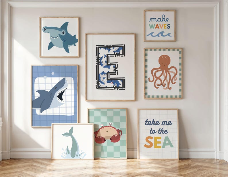 Puede incluir: Una colecci&oacute;n de l&aacute;minas art&iacute;sticas enmarcadas con vida marina y frases tem&aacute;ticas del oc&eacute;ano. Incluye un tibur&oacute;n martillo, un tibur&oacute;n con la boca abierta, una cola de ballena, un cangrejo, un pulpo y las frases "make waves" y "take me to the SEA".