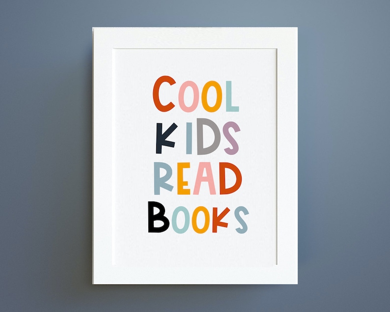 May include: A white framed wall art print featuring the text COOL KIDS READ BOOKS in a multi-colored sans-serif font. The letters are displayed in shades of orange, yellow, light blue, dark gray, light gray, pink, and black against a white background.