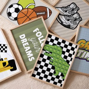 Puede incluir: Una colecci&oacute;n de l&aacute;minas de arte enmarcadas con diversas ilustraciones que incluyen un bal&oacute;n de f&uacute;tbol, baloncesto, f&uacute;tbol americano, pelota de tenis, zapatillas blancas, un dinosaurio pop-it verde sobre fondo de cuadros y el texto FOLLOW YOUR DREAMS.