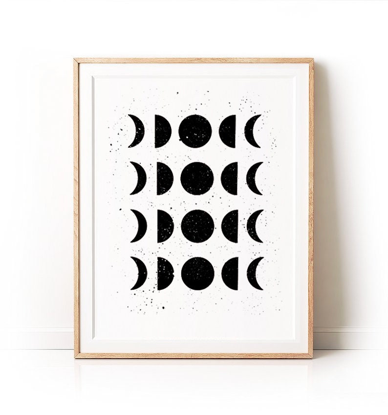 May include: Black and white print of a moon phases design in a wooden frame. The print features a repeating pattern of moons in different phases, from a crescent to a full moon.