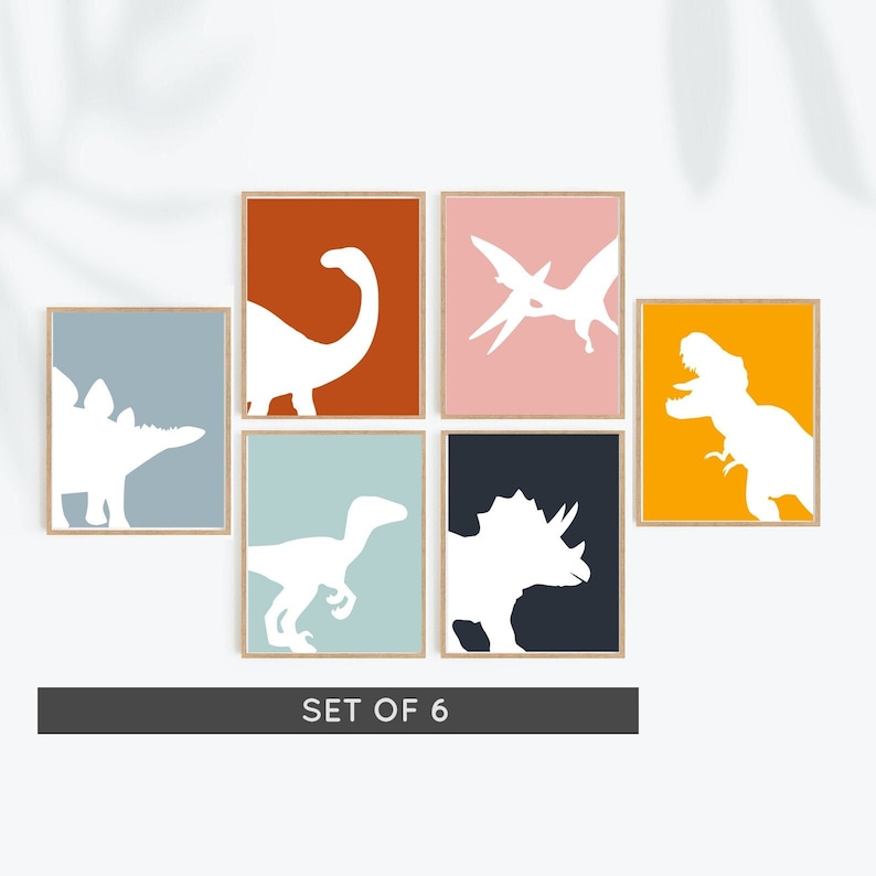 May include: Set of six dinosaur silhouette prints in various colors, including orange, blue, pink, and green. Each print features a different dinosaur silhouette in white against a solid color background. The prints are framed in a light wood frame.