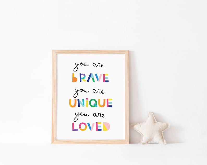 May include: A framed print with the text "You are brave, you are unique, you are loved" in colorful, geometric letters. The print is on a white background and has a light wood frame.
