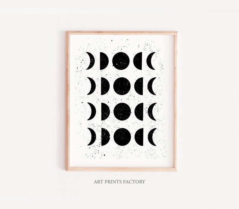 May include: Black and white print of a moon phases design with a speckled background. The print is framed in a light wood frame.