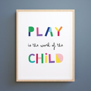 May include: A framed print with the text "PLAY is the work of the CHILD" in colorful, geometric letters. The letters are made up of different colored shapes.