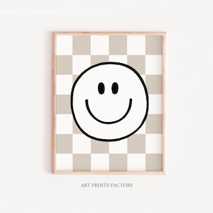 Op de afbeelding: Een zwart-witte smiley-gezichtsgrafiek op een beige en witte geruite achtergrond. De grafiek is gecentreerd op de print. De print heeft een houten frame. De tekst "ART PRINTS FACTORY" staat onderaan de print.