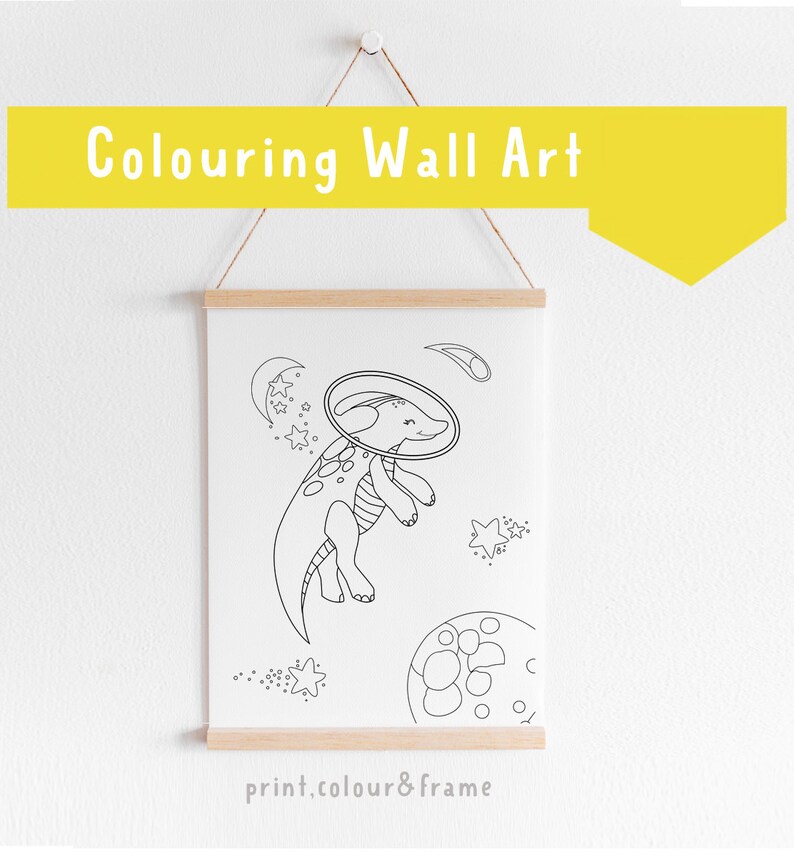 May include: Black and white line art print of a dinosaur wearing a space helmet and floating in space. The dinosaur is surrounded by stars and a crescent moon. The print is framed and ready to be colored in.