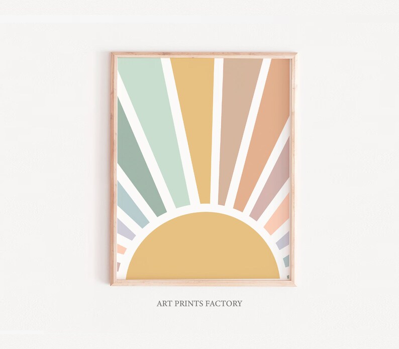 May include: A framed print of a colourful abstract sunburst design with a yellow sun in the centre. The sunburst is made up of pastel colours, including light blue, green, pink, and orange. The print is framed in a light wood frame.