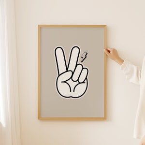 Op de afbeelding: Een ingelijst print met een zwart-witte illustratie van een vredesteken met een bliksemsymbool. De achtergrond is licht beige.