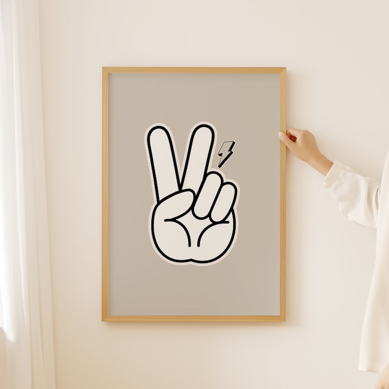 Op de afbeelding: Een ingelijst print met een zwart-witte illustratie van een vredesteken met een bliksemsymbool. De achtergrond is licht beige.