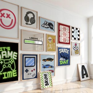 Puede incluir: Una pared de galer&iacute;a con varios cuadros enmarcados con temas de juegos y cultura pop, incluyendo un mando de juego estilo ne&oacute;n, una barra de carga, un esqueleto, zapatillas, una consola port&aacute;til, coches de carreras, patinetas y boletos.