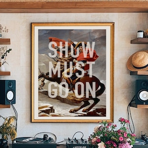 Puede incluir: Una impresión enmarcada de una pintura de un hombre a caballo, con las palabras "SHOW MUST GO ON" superpuestas sobre la imagen.
