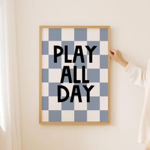 May include: A framed print with a blue and white chequered background and the text "PLAY ALL DAY" in black.