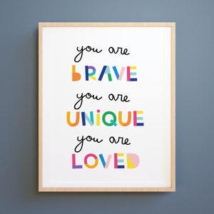 May include: A framed print with the text "You are brave, you are unique, you are loved" in colorful, block letters.