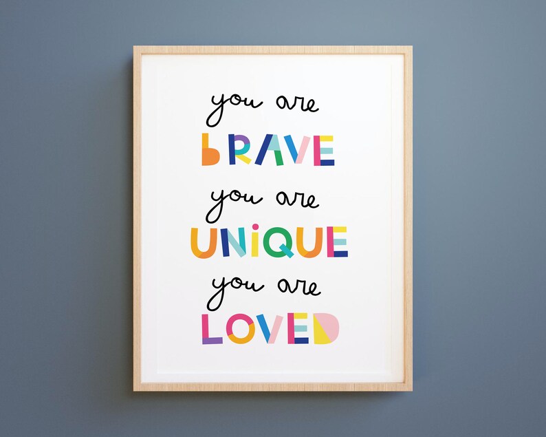 May include: A framed print with the text "You are brave, you are unique, you are loved" in colorful, block letters.